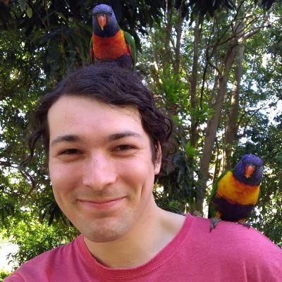 picture of trent smiling with Rainbow Lorikeets on his shoulder